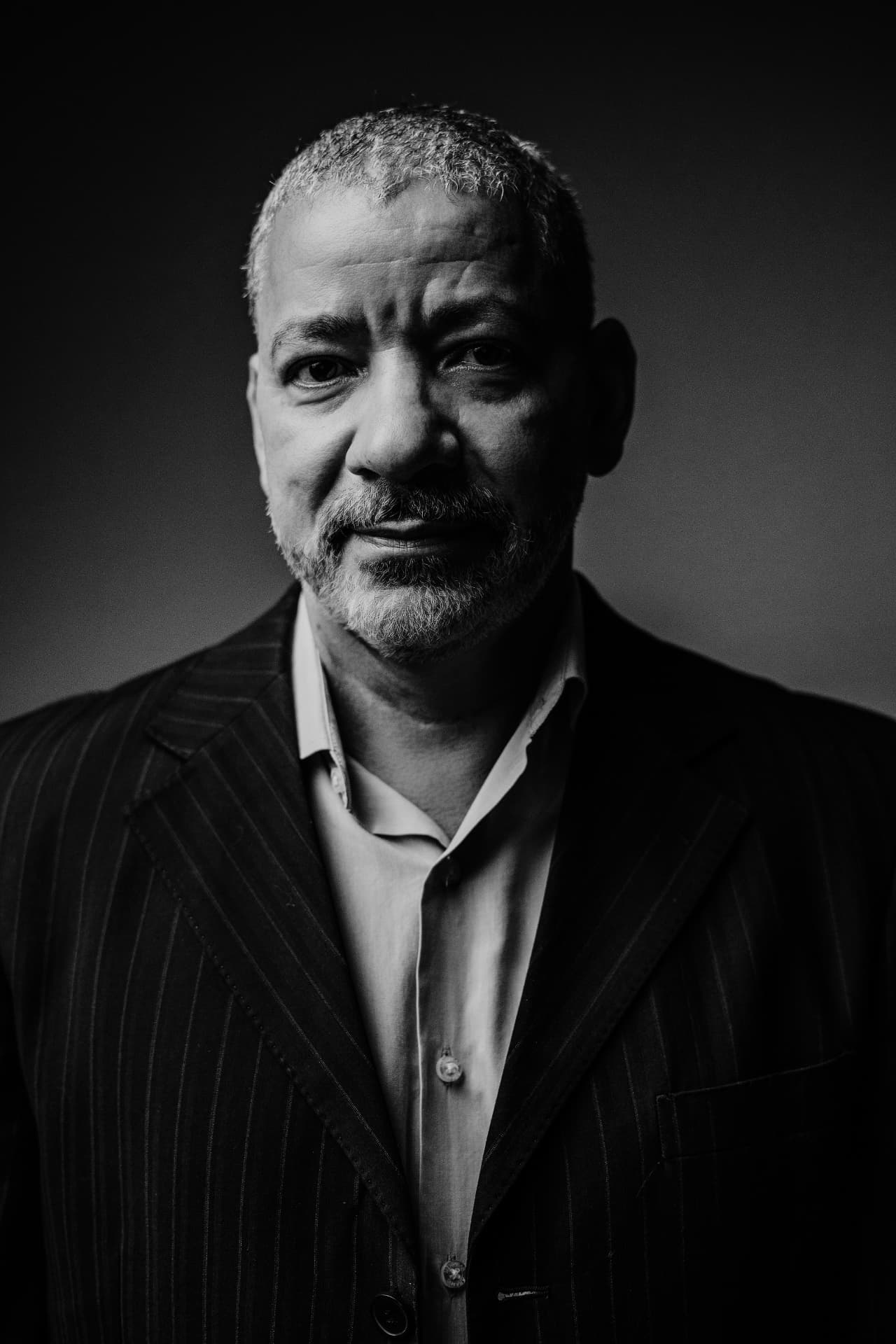 Retrato editorial em preto e branco de Lucian Rabello com terno listrado