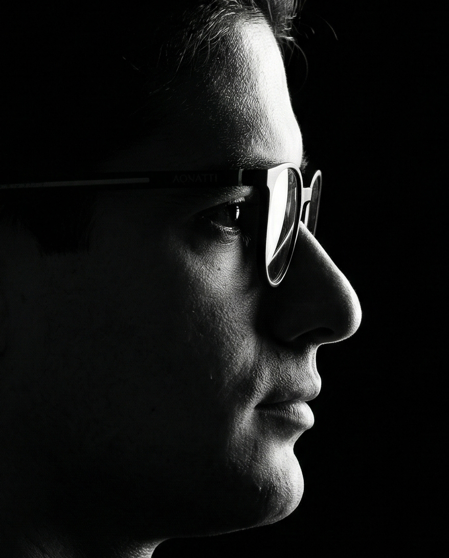 Retrato editorial em preto e branco de Lucian Rabello de perfil com óculos