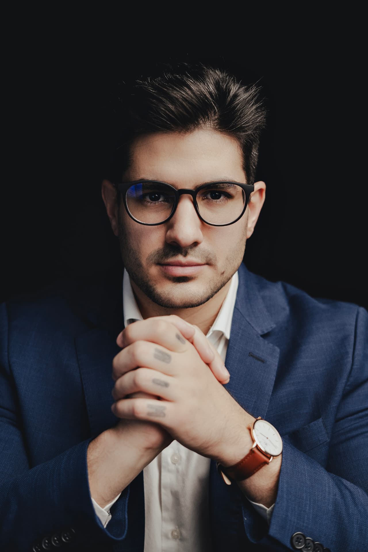 Lucian Rabello em retrato editorial com blazer azul e óculos